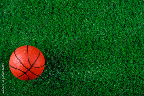 Top view of basketball ball on green grass background.