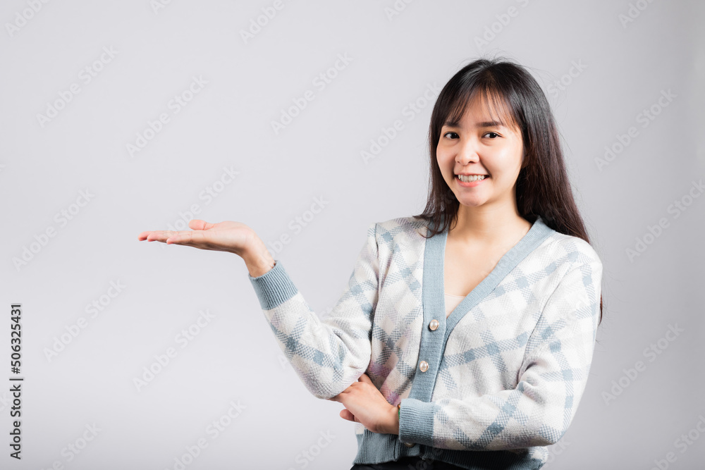 Smiling happy woman presenting product holding something on palm away side, Portrait Asian beautiful young female show hand demonstrate gesture studio shot isolated on white background with copy space Smiling happy woman presenting product holding something on palm away side, Portrait Asian beautiful young female show hand demonstrate gesture studio shot isolated on white background with copy space