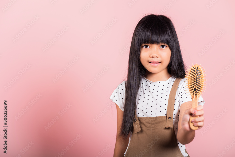 Asian little kid 10 years old hold comb brushing her unruly she touching her long black hair at studio shot isolated on pink background, Happy child girl with a hairbrush, Hair care concept Asian little kid 10 years old hold comb brushing her unruly she touching her long black hair at studio shot isolated on pink background, Happy child girl with a hairbrush, Hair care concept