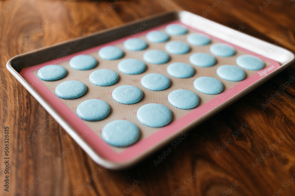Bakery. Making macaroons. Blue macarons ready for baking lie on a tray on a wooden table. Biscuit Bakery. Making macaroons. Blue macarons ready for baking lie on a tray on a wooden table. Biscuit