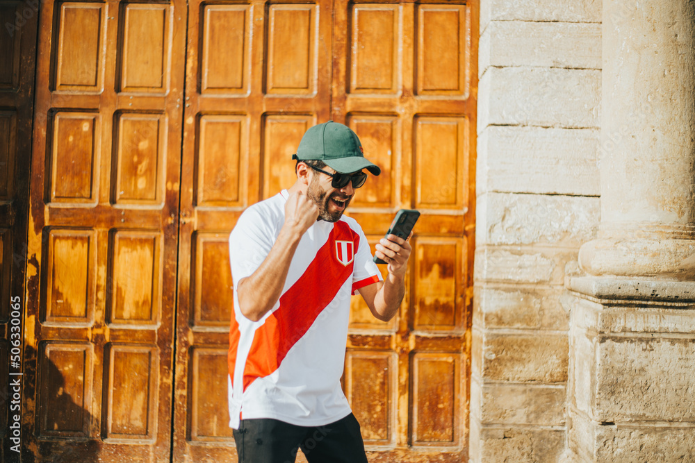 Hincha peruano de futbol celebrando un gol mirando su telefono en un parque de peru. Concepto de Personas y deportes.