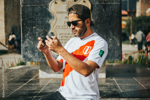 Hincha de futbol peruano sosteniendo su teléfono. Concepto de personas y tecnología. photo