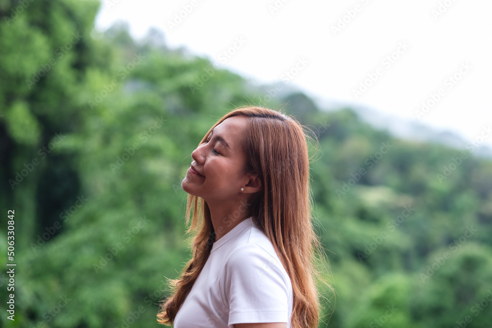 Portrait image of a young woman closed her eyes and enjoy a beautiful mountains and nature view