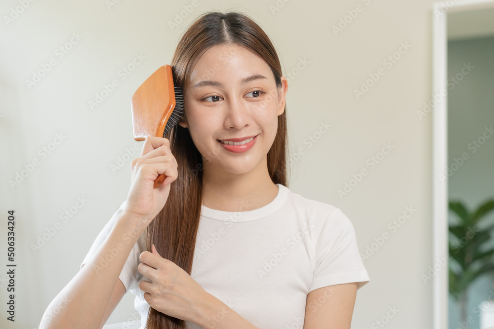 Health hair care, beauty makeup asian woman, girl holding hairbrush and brushing, combing her long straight hair looking at reflection in mirror in morning routine after salon treatment, hairstyle. Health hair care, beauty makeup asian woman, girl holding hairbrush and brushing, combing her long straight hair looking at reflection in mirror in morning routine after salon treatment, hairstyle.
