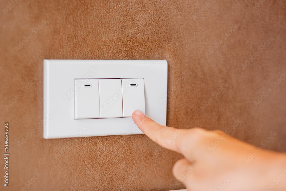 finger turn on or off on light switch on wall at home. Energy Saving, power, electrical and lifestyle concepts finger turn on or off on light switch on wall at home. Energy Saving, power, electrical and lifestyle concepts