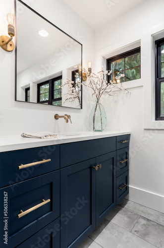 Beautiful bathroom in new luxury home. Features vanity with faucet  sink  mirror  cabinets  and sconce lights.