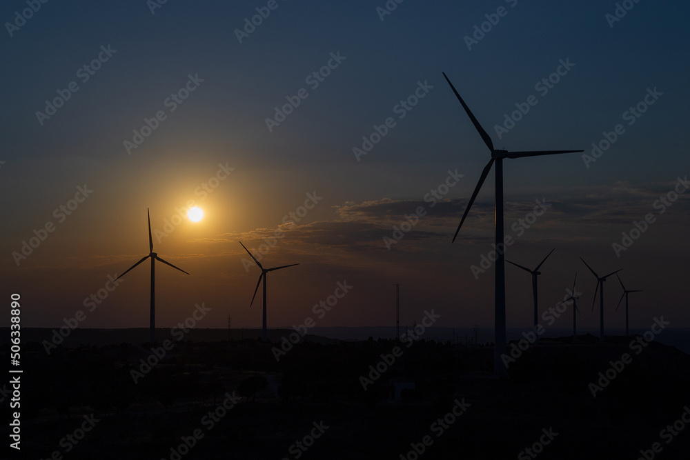 Obraz premium Sunset over a windmill park. An example of renewable energy, clean nature and a sustainable future. Earth Day
