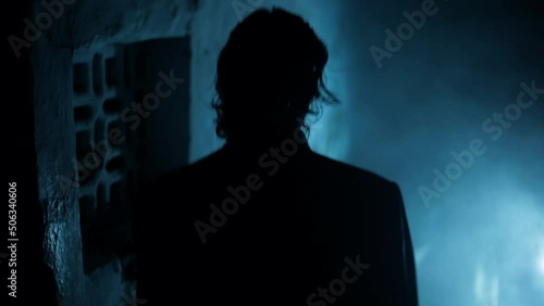 Professional hitman in a suit with a gun in his hand, walking down the stairs, dramatic lighting and smoke. photo