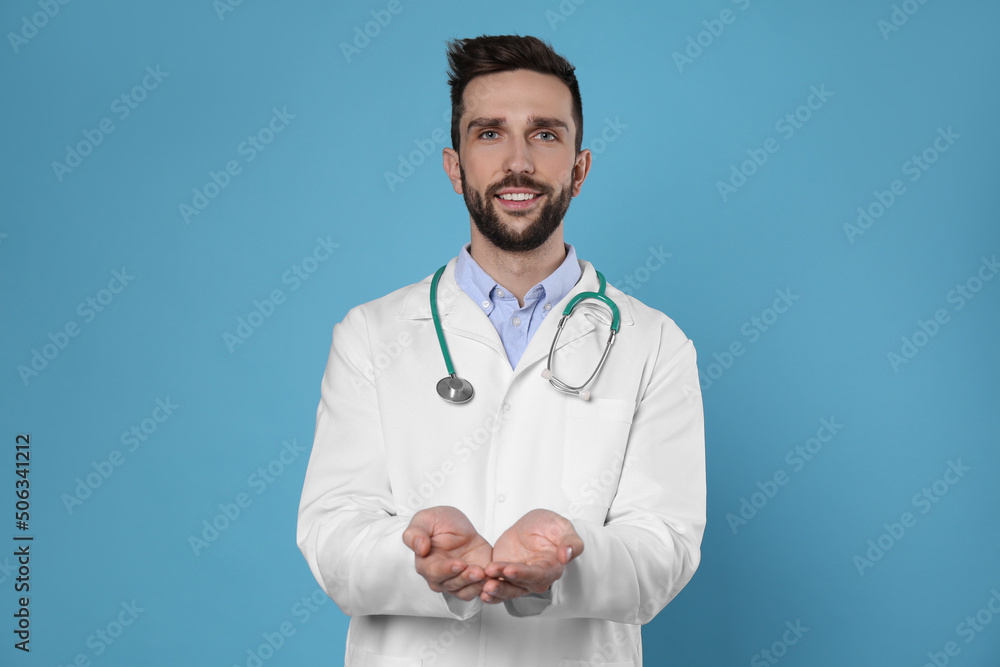 Doctor with stethoscope holding something on light blue background. Cardiology concept Doctor with stethoscope holding something on light blue background. Cardiology concept