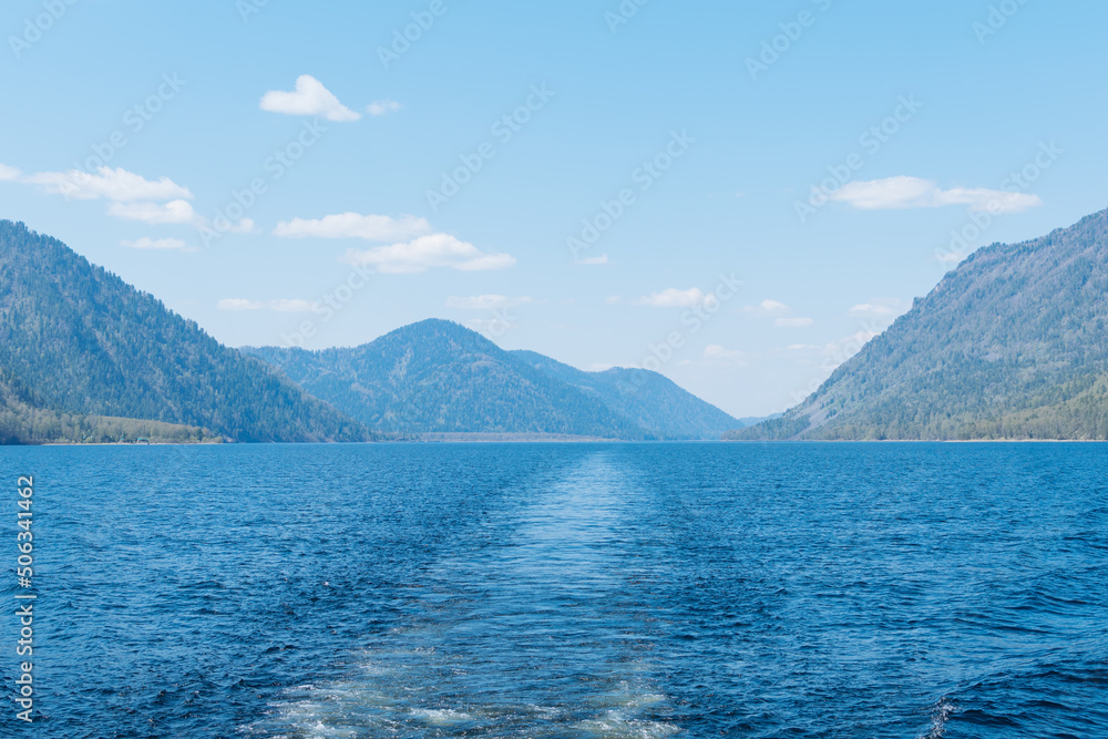 Straight ship trace and landscape with mountains and lake. Altai Republic, Lake Teletskoye.