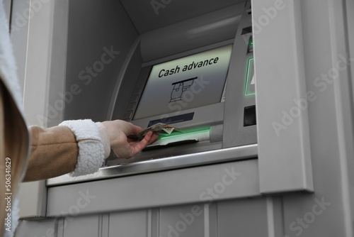 Woman using cash machine for money withdrawal outdoors, closeup