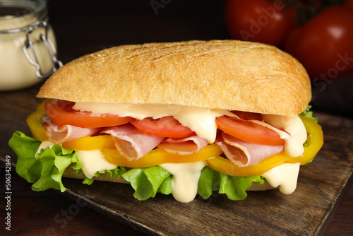 Delicious sandwich with vegetables, ham and mayonnaise on wooden table, closeup