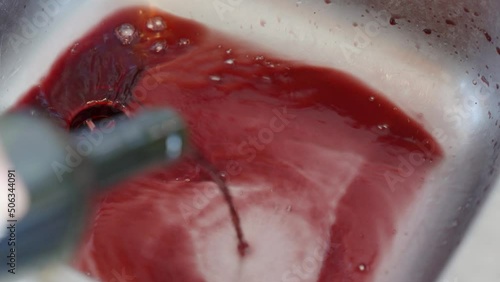 Person pouring a bottle of red wine down the sink in the kitchen. Stop drinking alcohol, healthy lifestyle