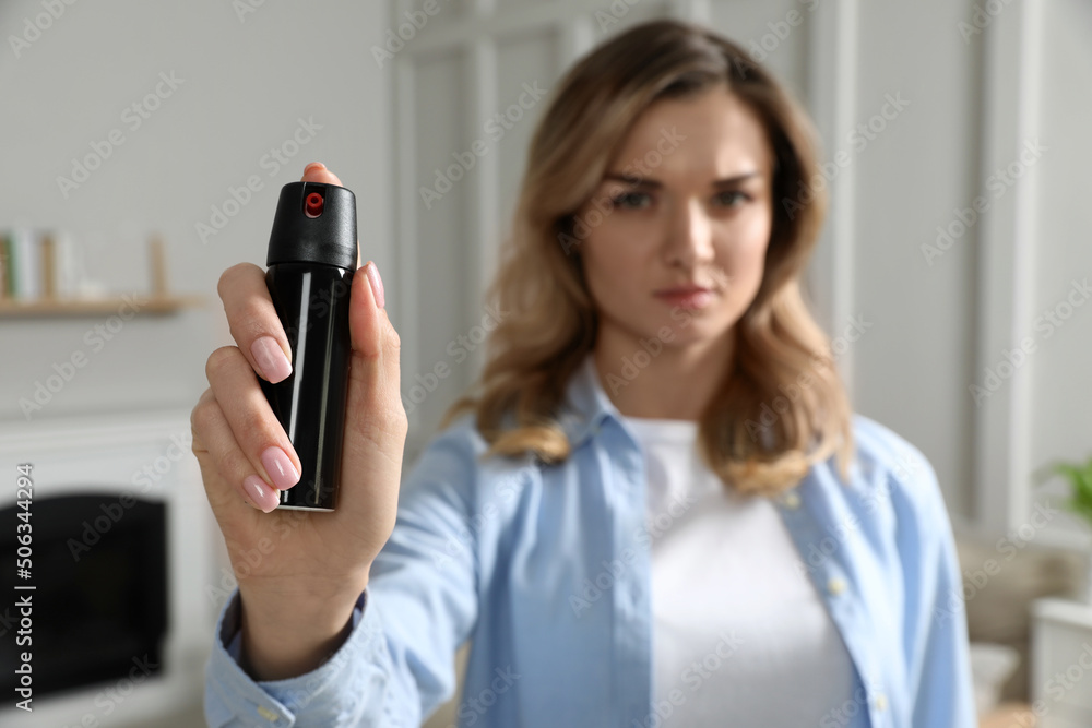 Young woman using pepper spray at home, focus on hand Young woman using pepper spray at home, focus on hand