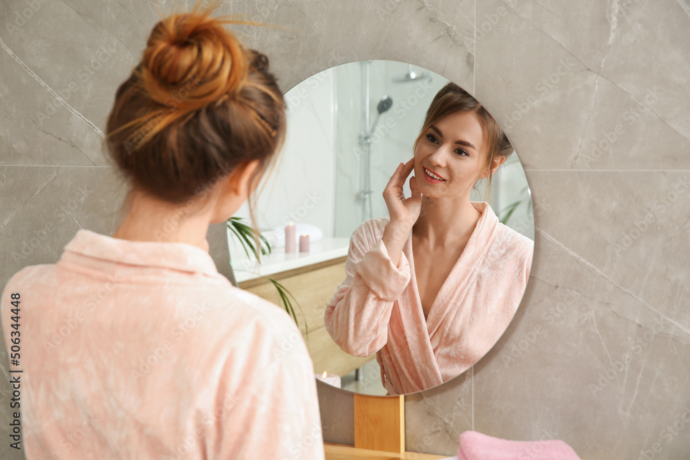 Beautiful woman wearing pink bathrobe in front of mirror at home - obrazy, fototapety, plakaty 
