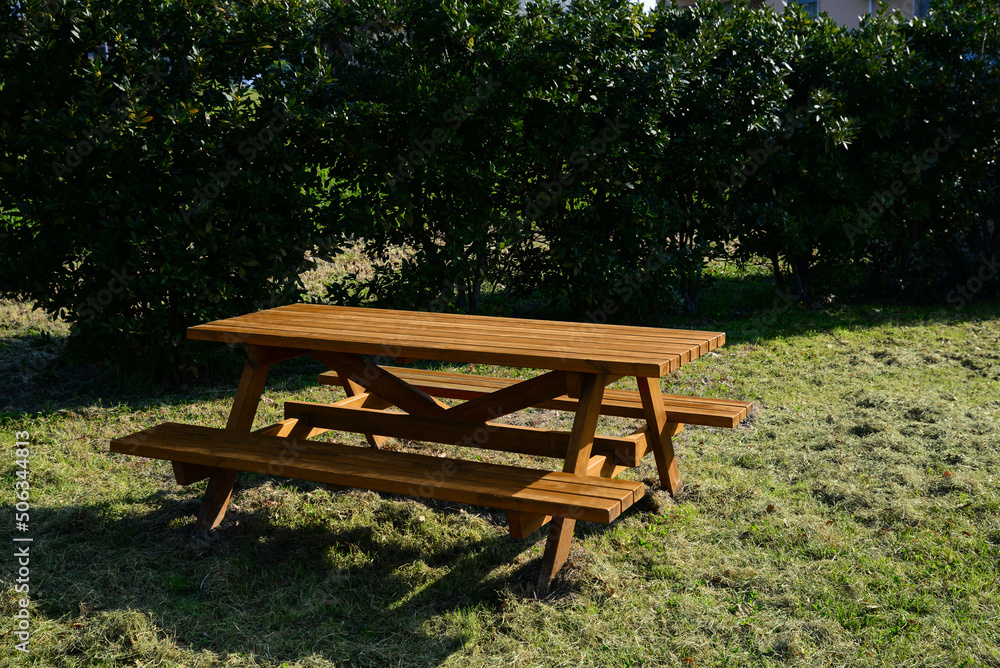 Empty wooden picnic table with benches in park on sunny day