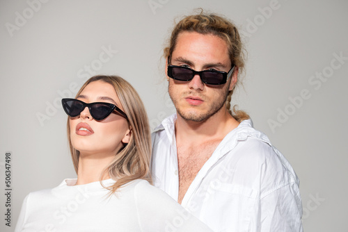 Couple in fashion black sunglasses. Young couple posing with sunglasses. Vogue Style. High fashion look in vogue style. Couple in love on date in formal fashion look. Trendy look.