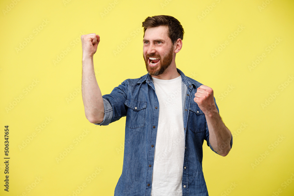 Happy joyful man doing winner gesture clenching fists and looks at side Happy joyful man doing winner gesture clenching fists and looks at side