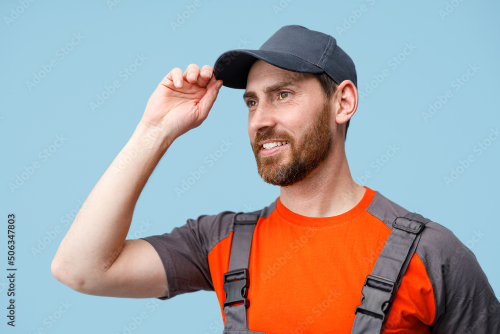 Close up of male worker in uniform holding cap and smile looking at side. Studio shoot Close up of male worker in uniform holding cap and smile looking at side. Studio shoot