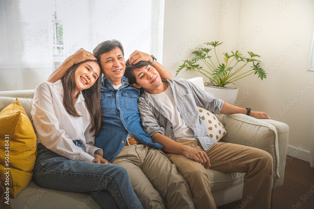 Happy asian family, father and son and daughter sitting on sofa in living room.