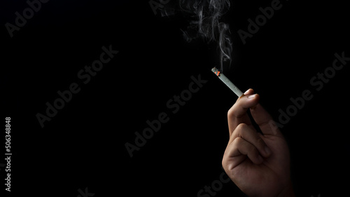 Closeup hand of man holding a cigarette.Tobacco cigarette Butt on the Floor in dark background for world Tobacco day concept or stop smoking
