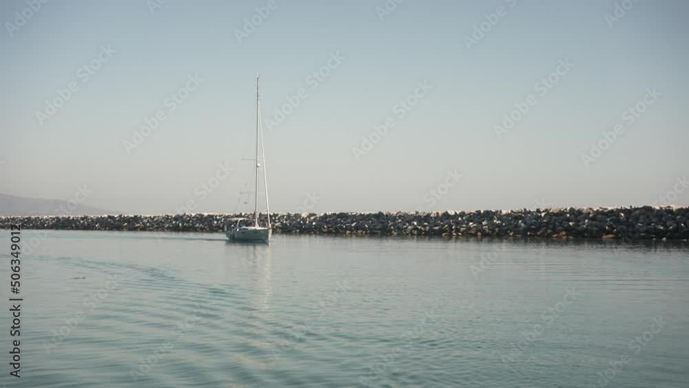 As a boat sets off to sea there are other sail boats following the lead ship during golden hour As a boat sets off to sea there are other sail boats following the lead ship during golden hour