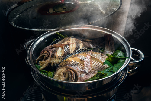 Two fish in a steamer set on the stove. The lid was opened and smoke floated.