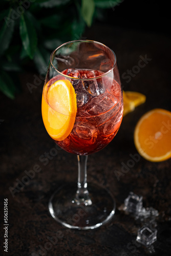 Shining cocktail Aperol spritz in a wine glass with ice and a slice of orange. Long drink cocktail with aperol and sparkling wine