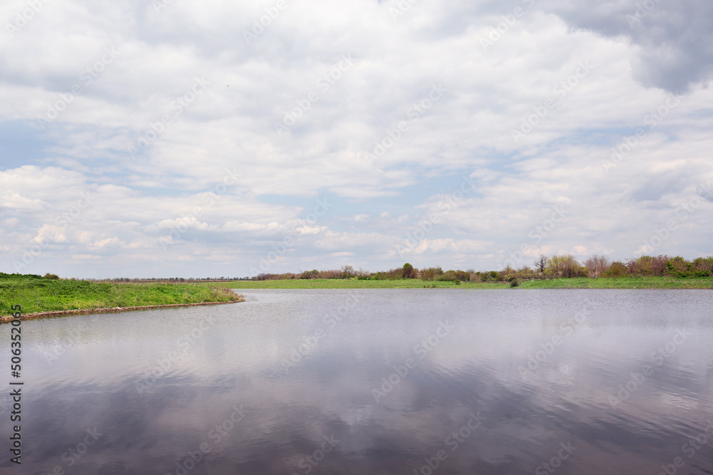 River near village under sky with clouds. Picturesque landscape