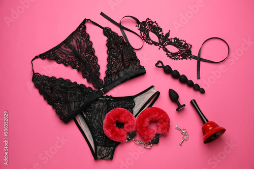 Sex toys, accessories and lingerie on pink background, flat lay photo