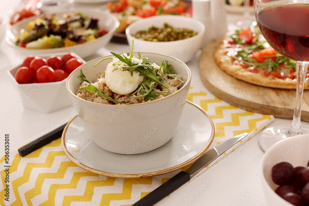 Bowl of oatmeal with poached egg, arugula and cheese served on buffet table for brunch