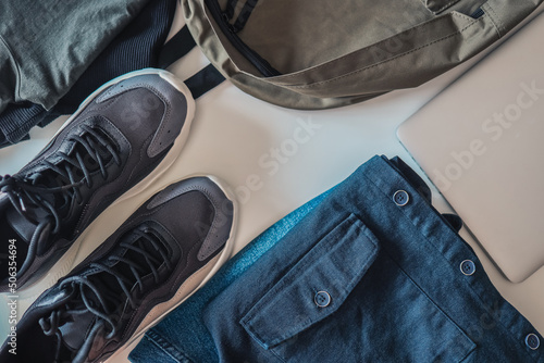 Set of men's things, flat lay top view. Sneakers, backpack, jeans and jacket on a white background