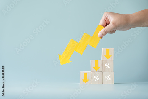 Yellow paper cut arrow going down negative trend on wooden blocks with percentages. Concept of profit decreasing in percentage.