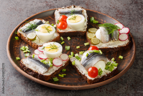 Estonian traditional delicacy kiluvoileib sandwich with fish, egg and butter close-up in a plate on the table. horizontal photo