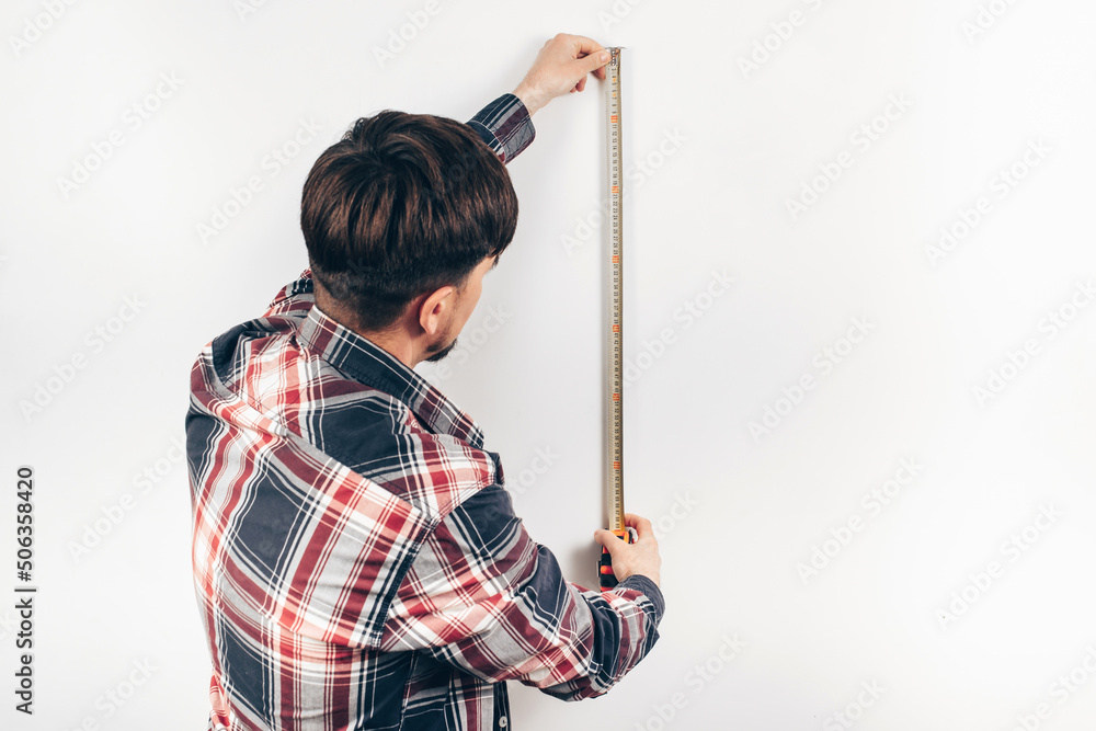 builder worker measuring white wall with construction tape measure builder worker measuring white wall with construction tape measure