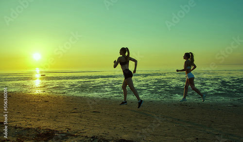two girl running by the sea on the beach