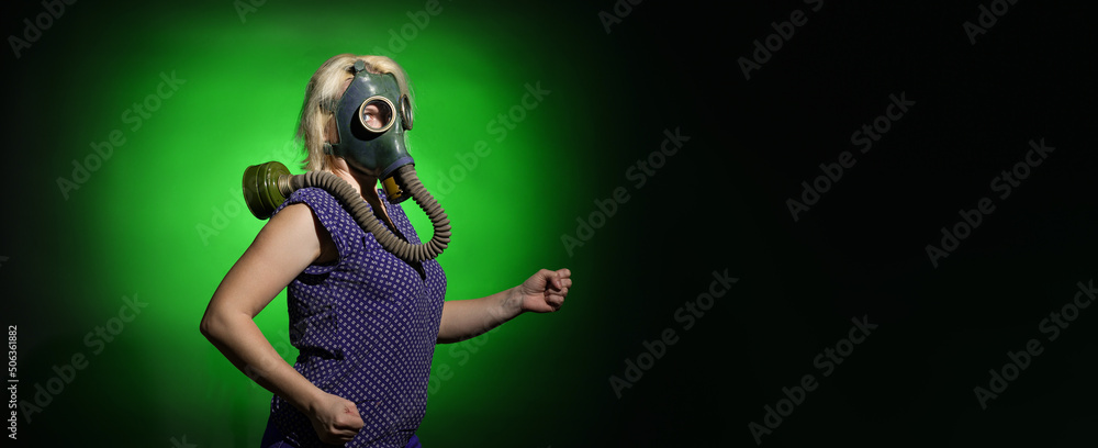 a woman in a gas mask walks on a dark background with copy space