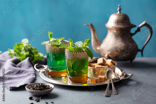 Moroccan mint tea in traditional glasses on silver tray. Grey and blue background. Copy space.