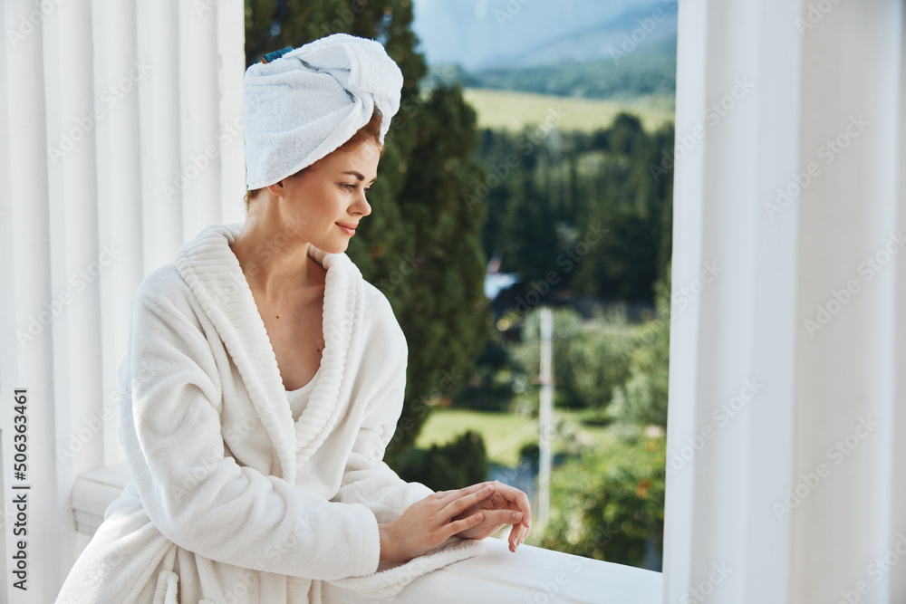 Attractive young woman with a towel on my head in a white bathrobe staying on the balcony in a hotel unaltered Attractive young woman with a towel on my head in a white bathrobe staying on the balcony in a hotel unaltered