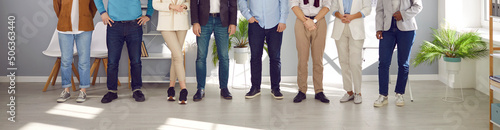 Team of people in smart casual clothes at work in office. Group of men and women in shirts and jackets, jeans and trousers standing together. Cropped, low section shot of human legs. Header background photo