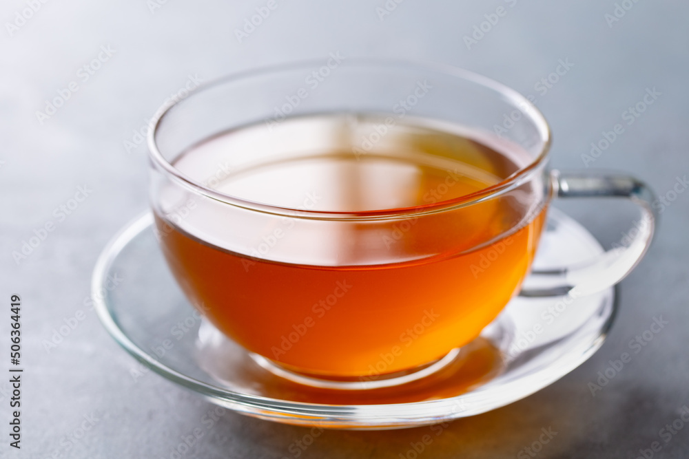 Tea in glass cup. Grey background. Close up. Tea in glass cup. Grey background. Close up.