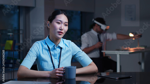 Asian corporate employee look at screen having video conference sitting at desk in modern office
