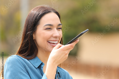 Foto Happy woman dictating message in the street on phone