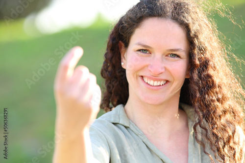 Happy candid woman saying come here in a park