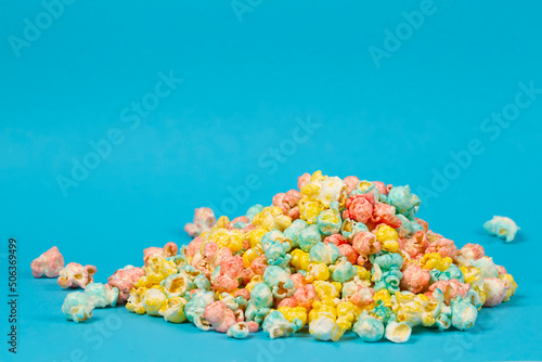 Multi-colored popcorn is scattered on a blue background. Colorful beautiful sweet dessert. photo