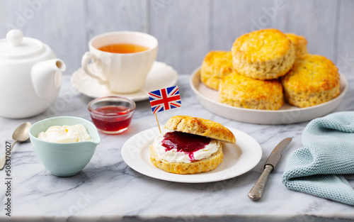 Scones, tea cakes with jam, clotted cream with the flag of Great Britain. Traditional British teatime. Grey background.