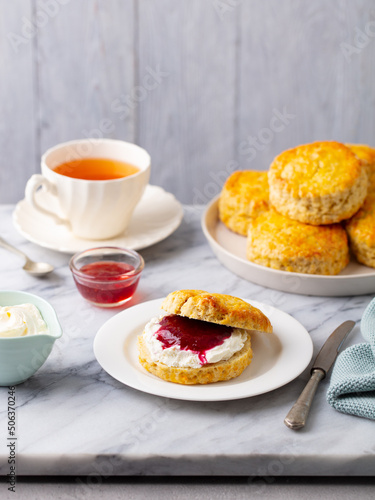 Scones with jam, clotted cream and cup of tea on marble table. Grey background. Copy space.