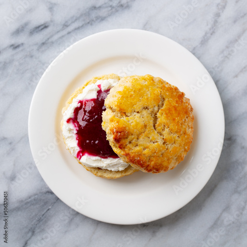 Scones, teacake with jam, clotted cream. Traditional British dessert. Marble background. Close up. Top view.