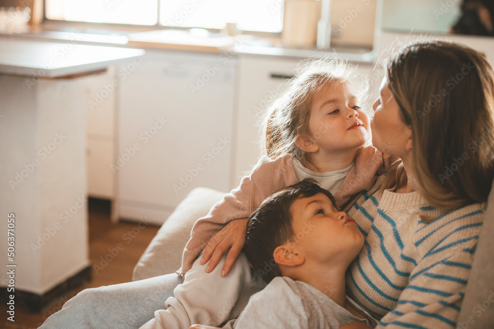 Young woman with daughter and son puckering at each other sitting on sofa Young woman with daughter and son puckering at each other sitting on sofa
