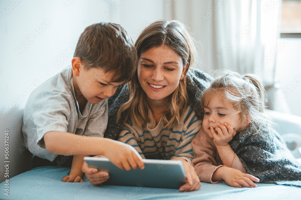 Smiling mother with son and daughter using tablet PC on bed Smiling mother with son and daughter using tablet PC on bed